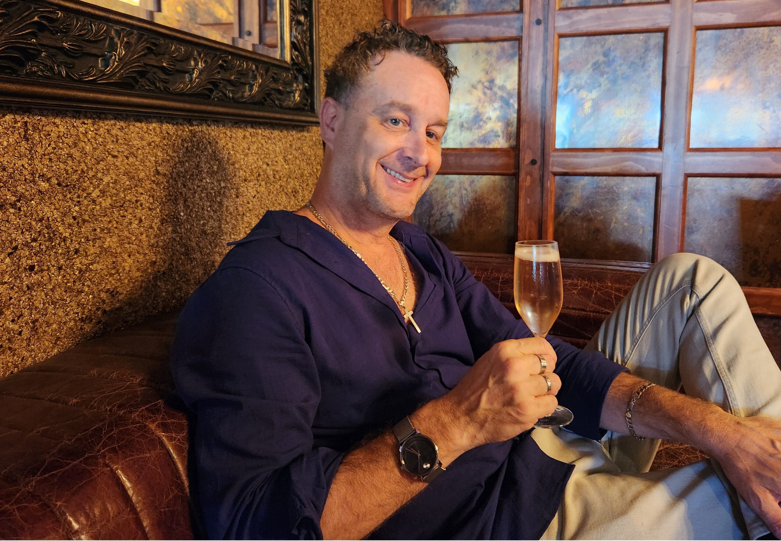 Mike DeSalvia seated at a table with a glass of Champagne, reflecting during his interview about 20 years in the wine industry.